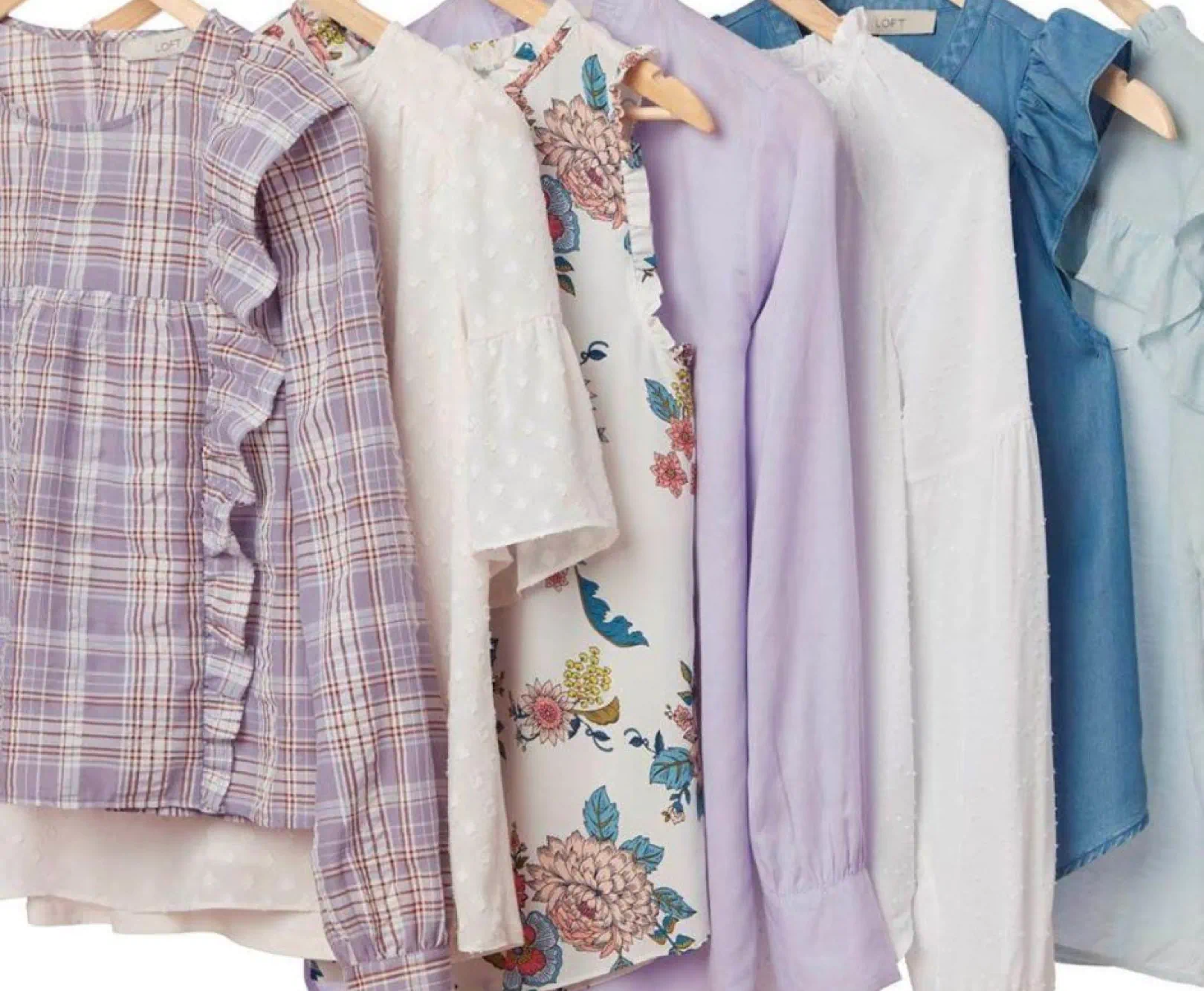 Six blouses on wooden hangers, featuring various colors and patterns, including plaid, floral, and polka dots.