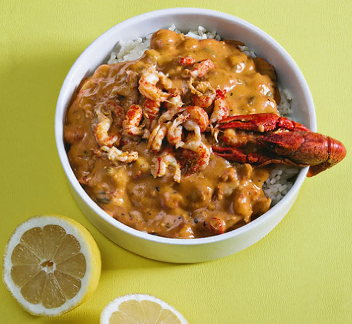 Bowl of rice, sauce and crawfish pieces, with a crayfish claw topper.