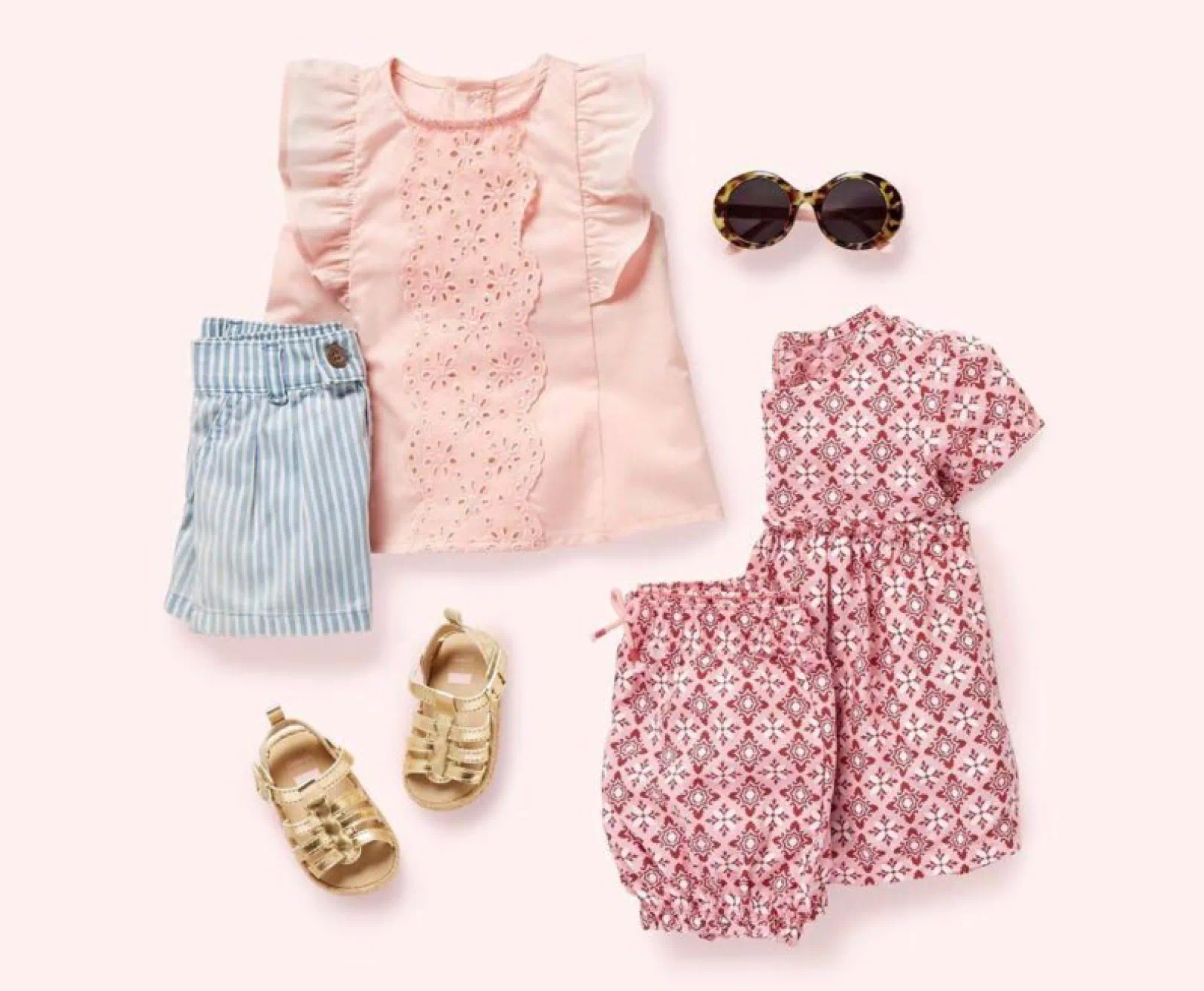 Children's clothing and accessories, including a pink top, striped shorts, gold sandals, tortoiseshell sunglasses, and a patterned dress with bloomers.