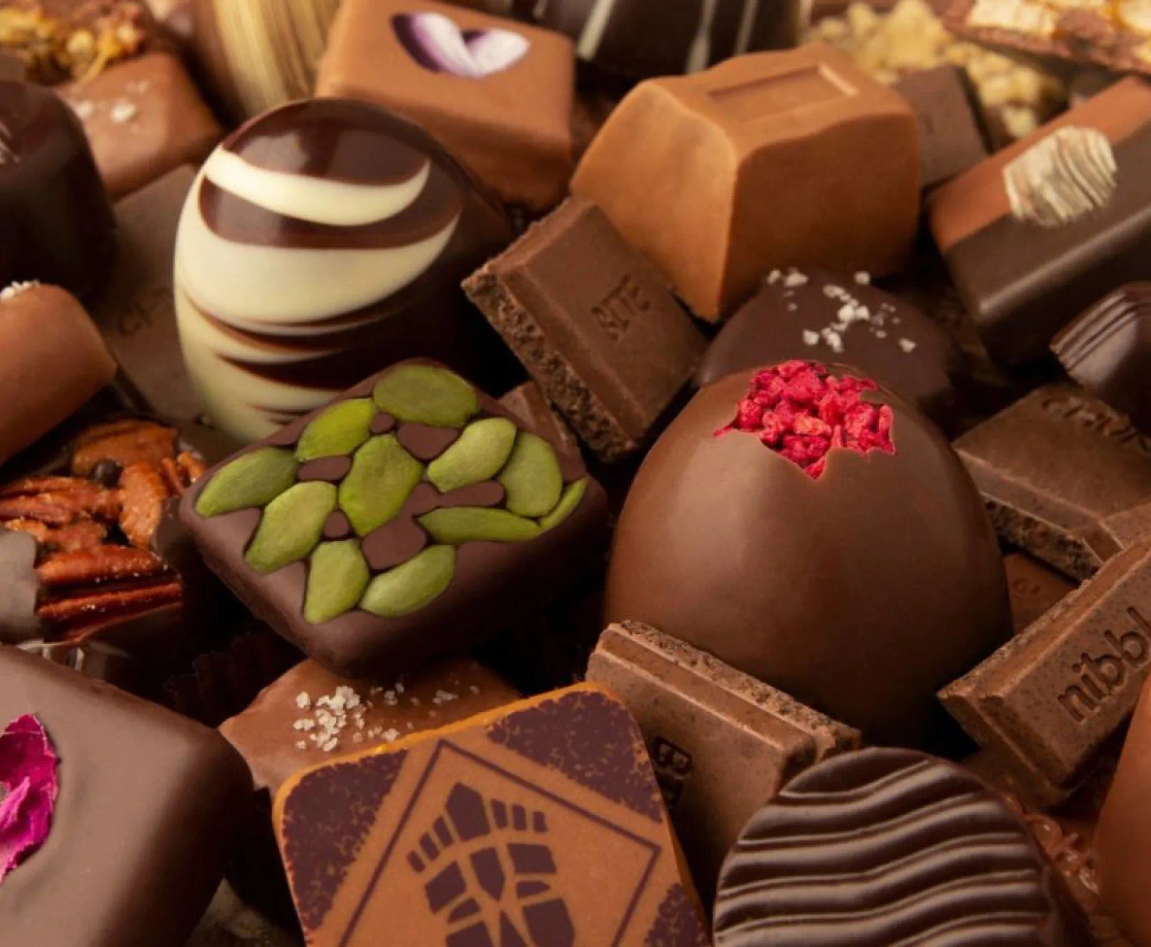 Assortment of gourmet chocolates and truffles with various toppings and designs.