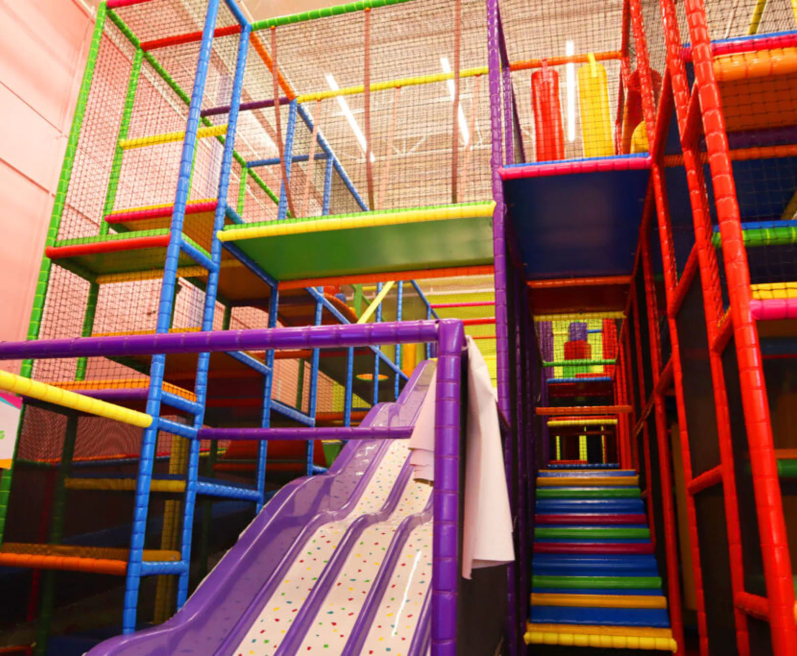 Colorful indoor playground structure with a purple slide and multi-level climbing frame.