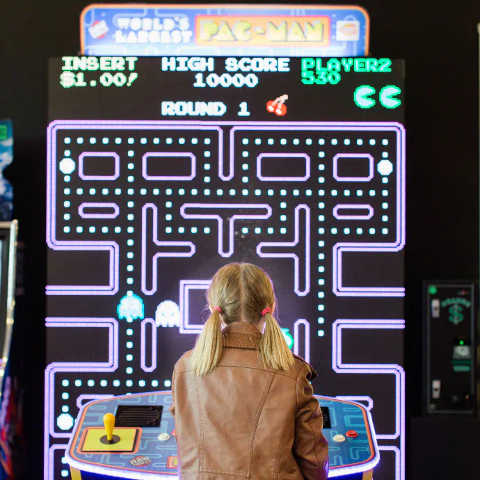 Young kid plays a larger version of the game "Pac-Man".