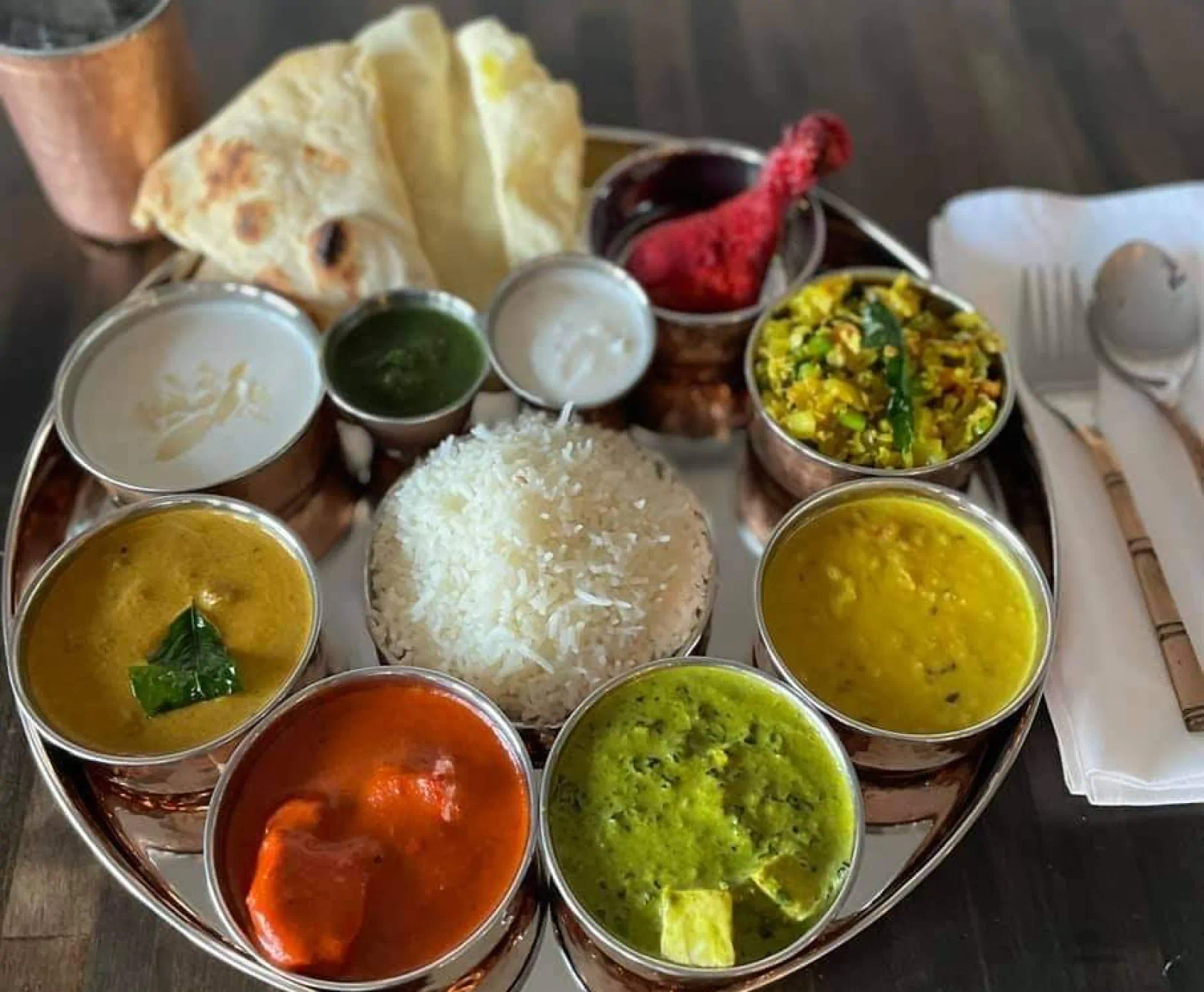 A large plate of Indian food served with rice, butter chicken, naan bread, and much more.