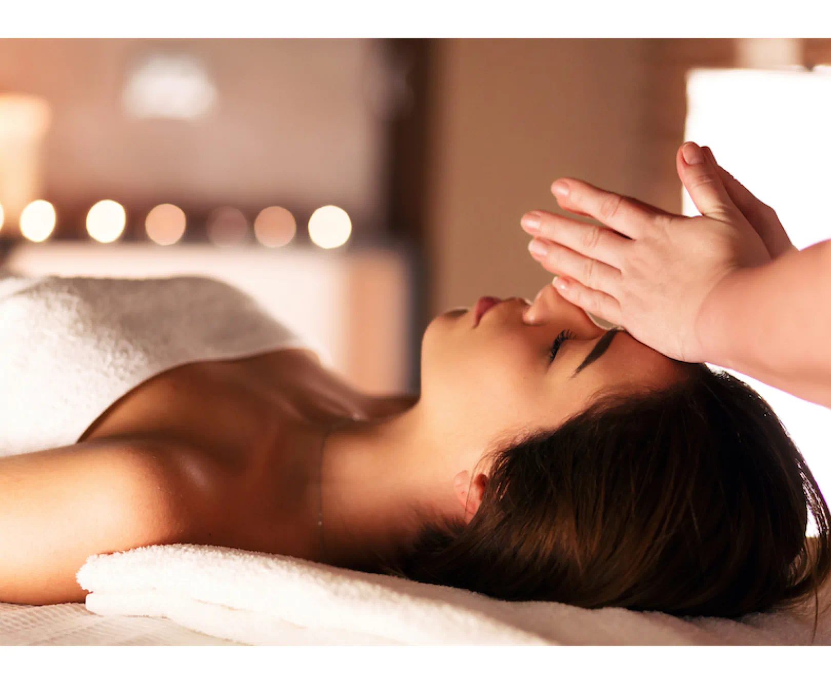 A woman lays down, covered in a towel as she receives a massage.