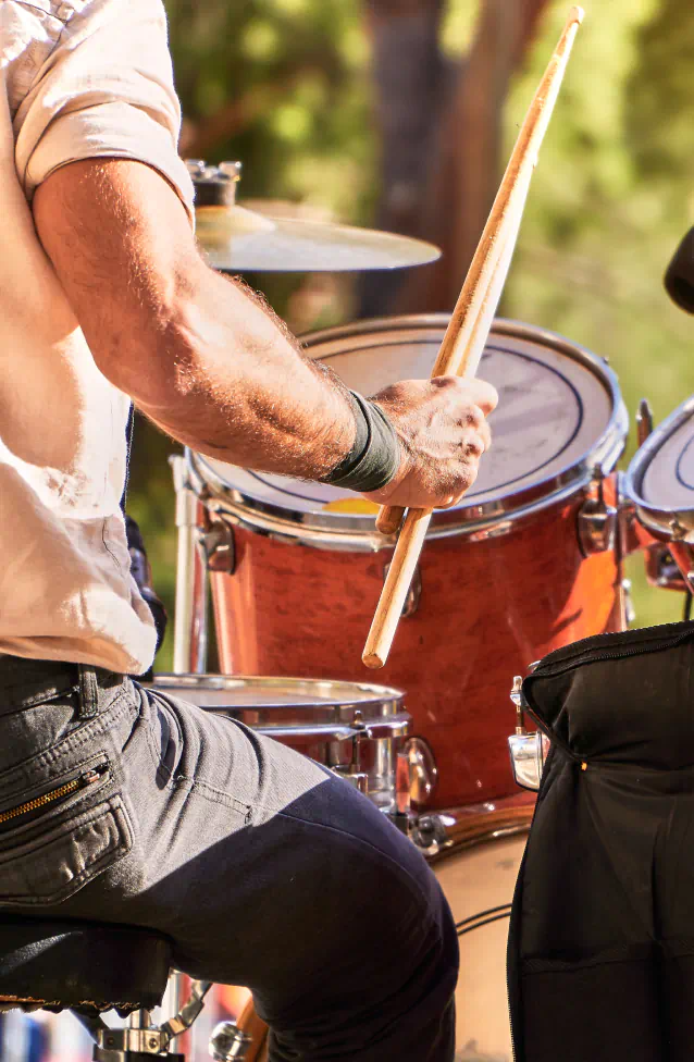 Close up view of a man sitting at a drum set, sticks in hand.