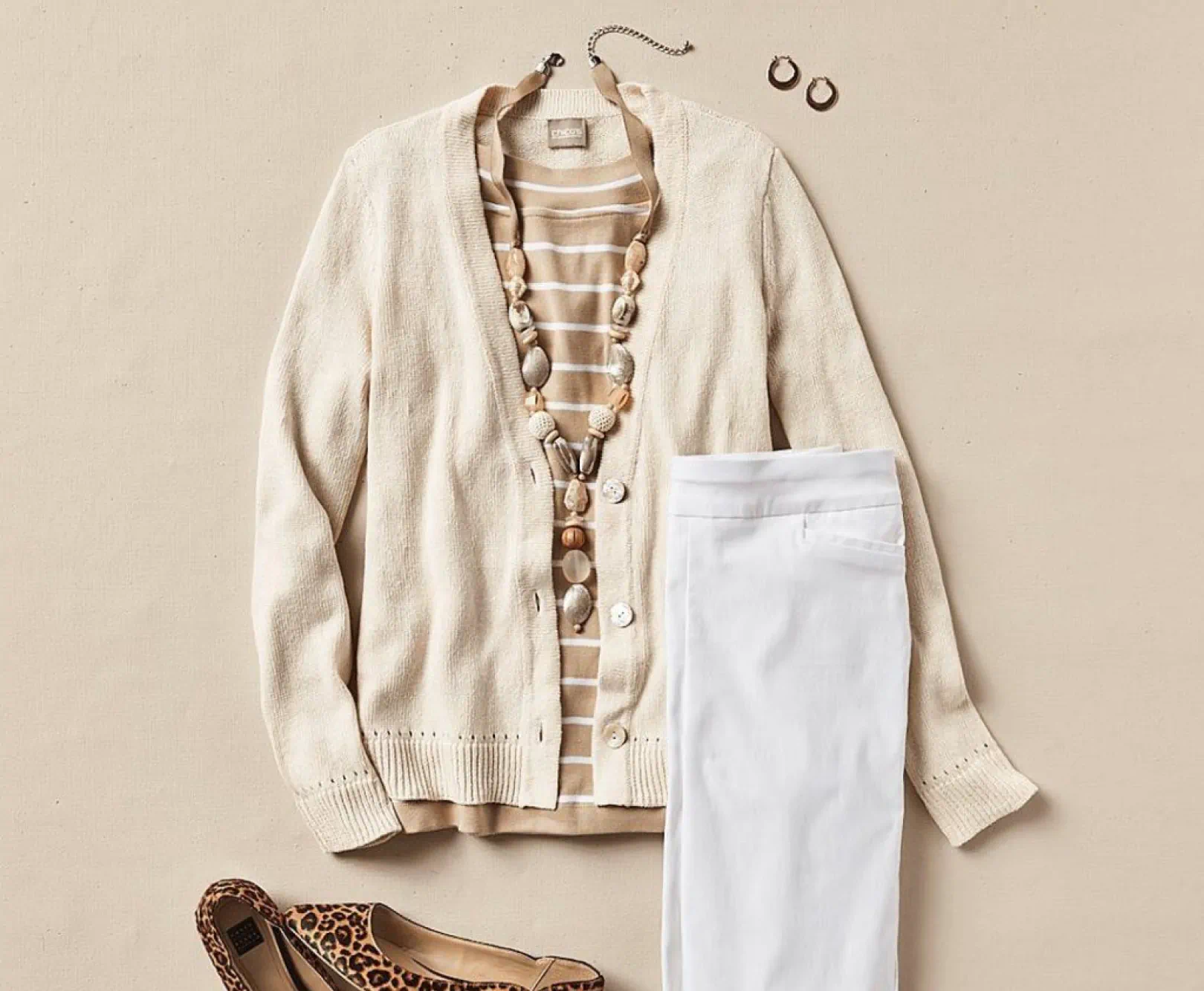 Flat lay of a beige cardigan, striped shirt, white pants, necklace, earrings, bracelet, and leopard print flats.