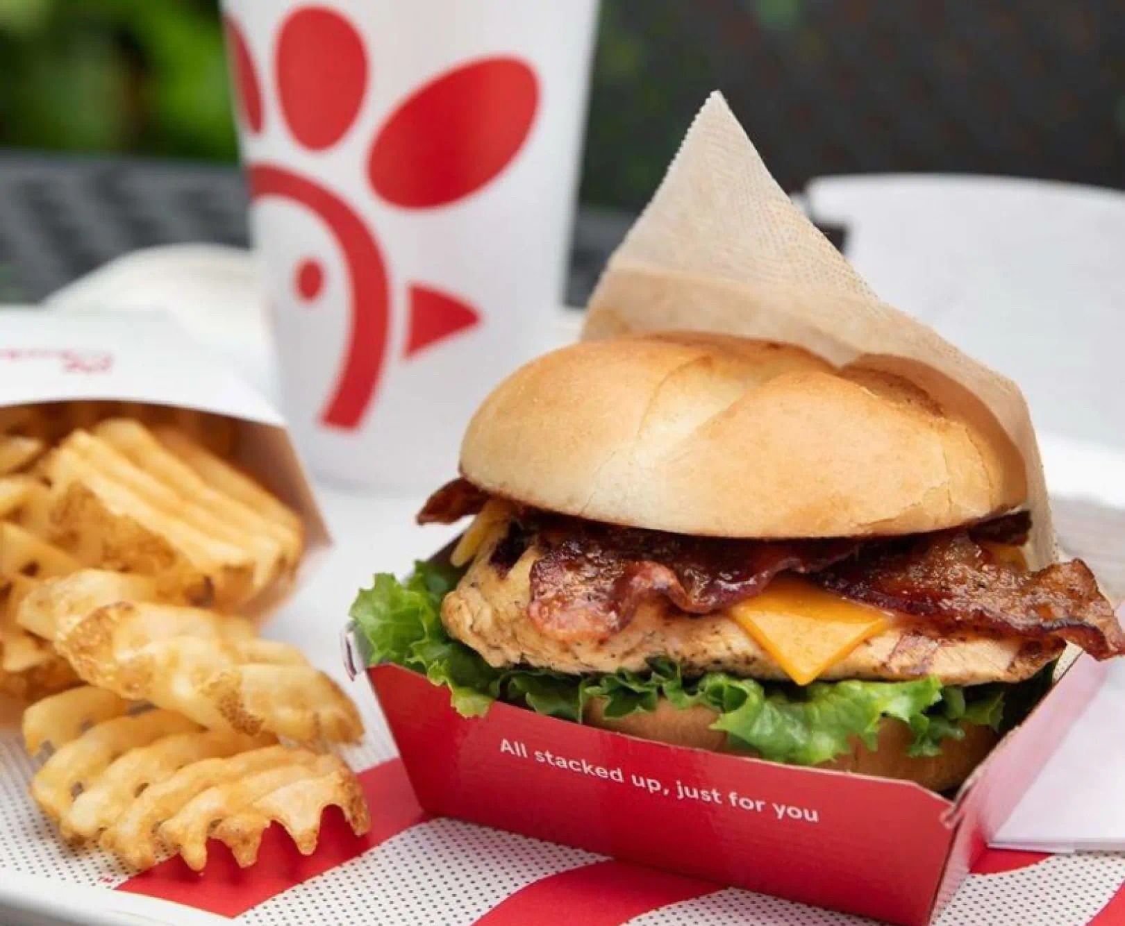 Chick-fil-A sandwich with waffle fries and a drink cup on a table.