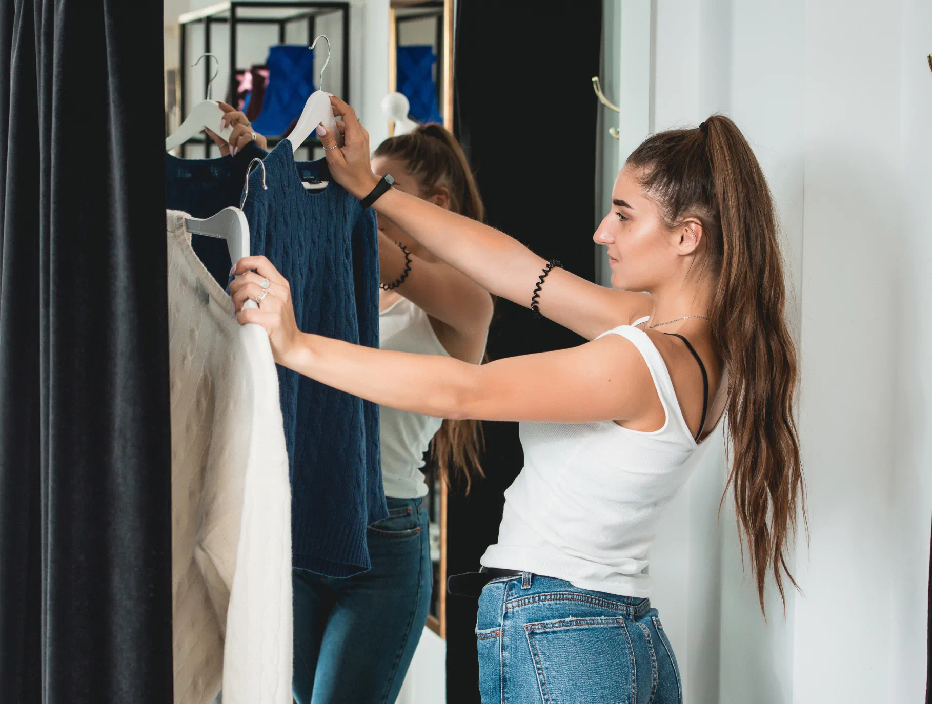 A woman considers two sweaters in a clothing store