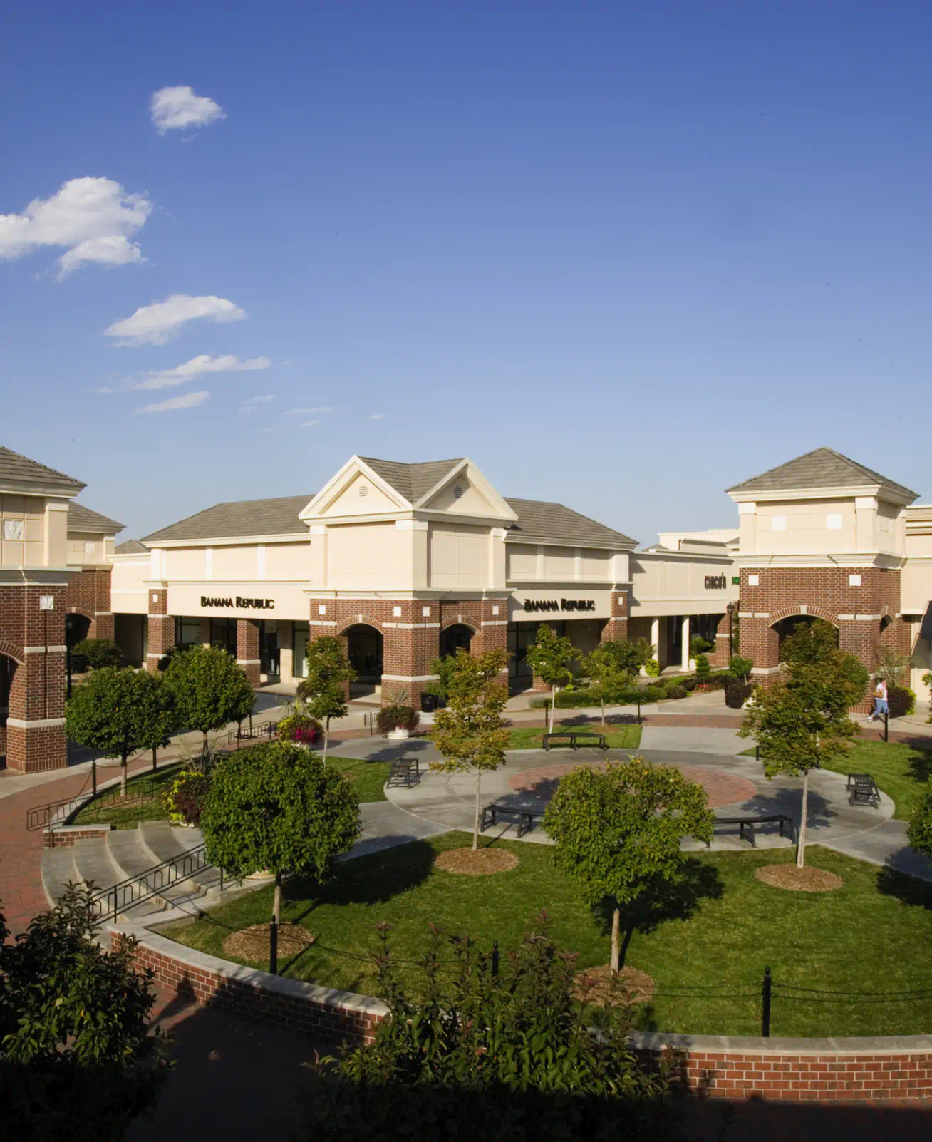 Aerial shot of a circular open space in the South Pointe Pavilions with benches, trees and grass. Store circle the space including "Banana Republic".