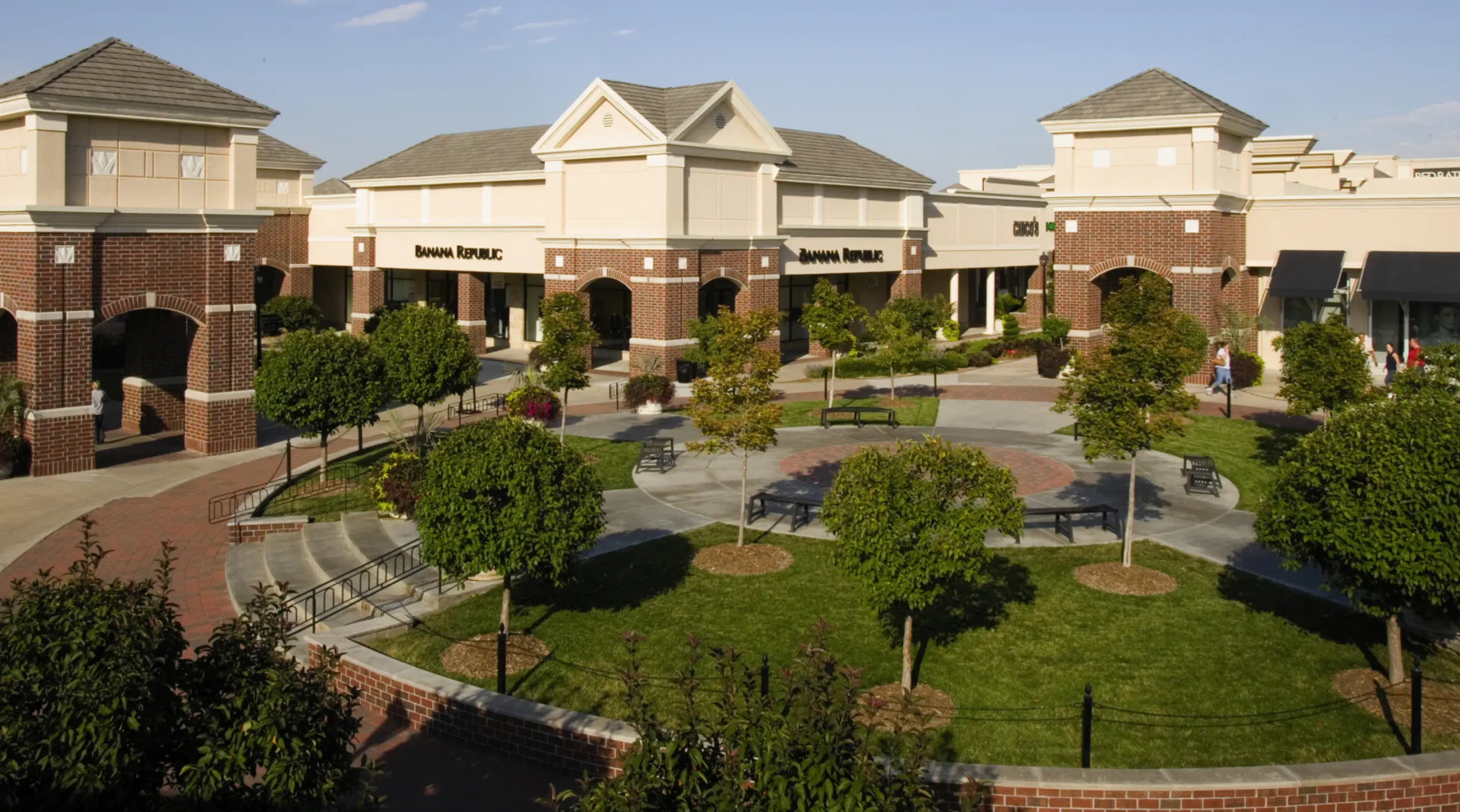 Aerial shot of a circular open space in the South Pointe Pavilions with benches, trees and grass. Store circle the space including "Banana Republic".