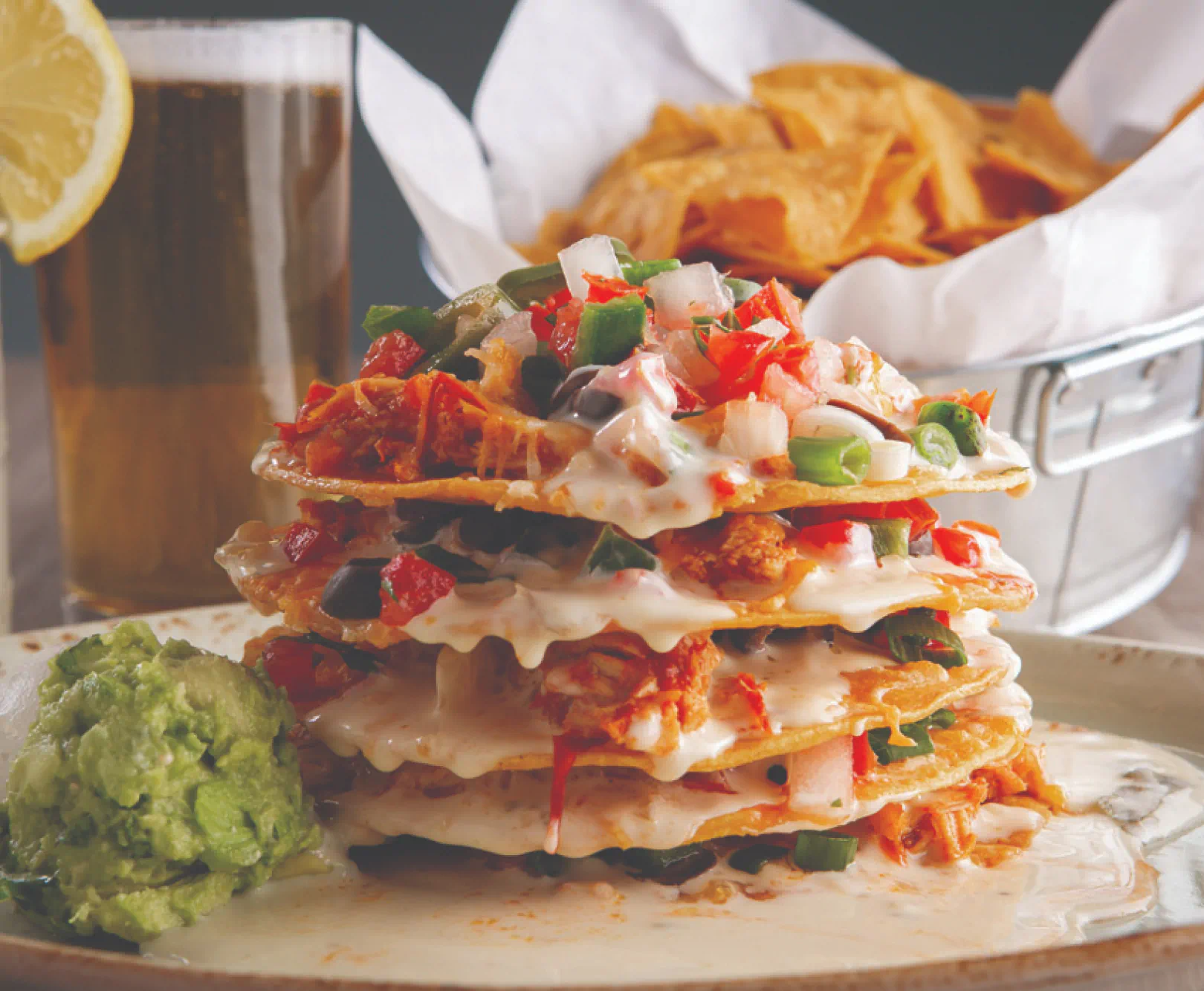 Four tostadas stacked on top of one another served with a side of guacamole.