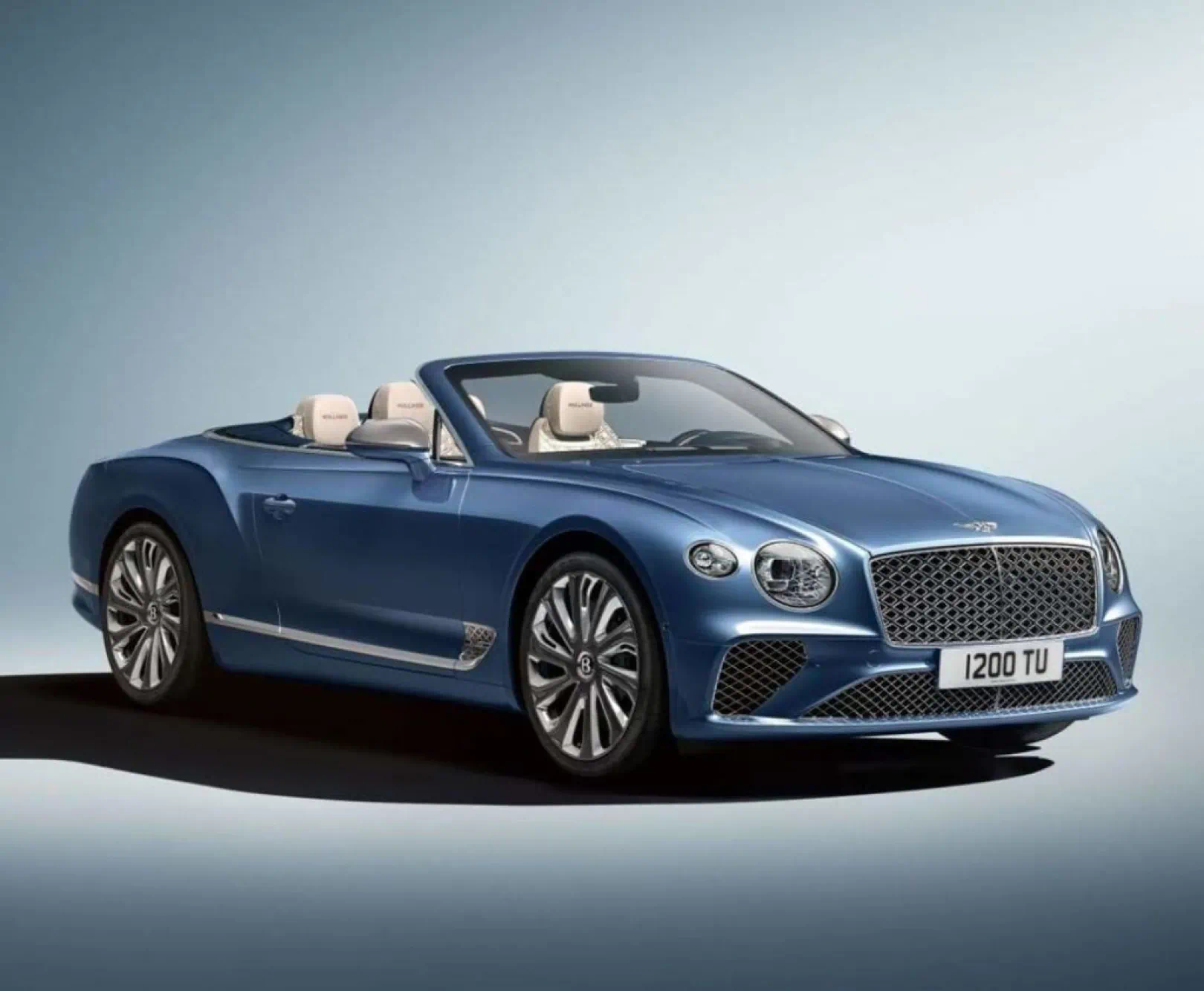 A blue Bentley sits against a white backdrop.