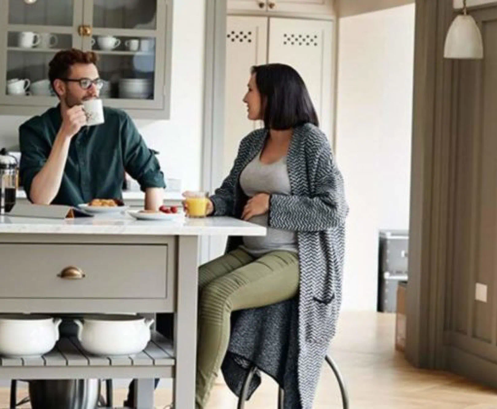 A couple sits at their kitchen center island enjoying a cup of coffee.