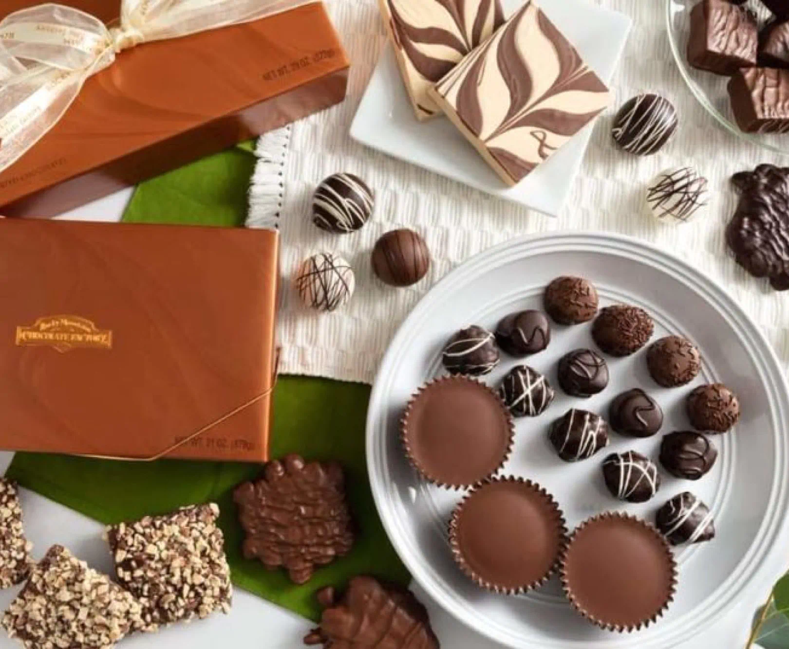 Several assorted chocolates lay on top of white dishes.