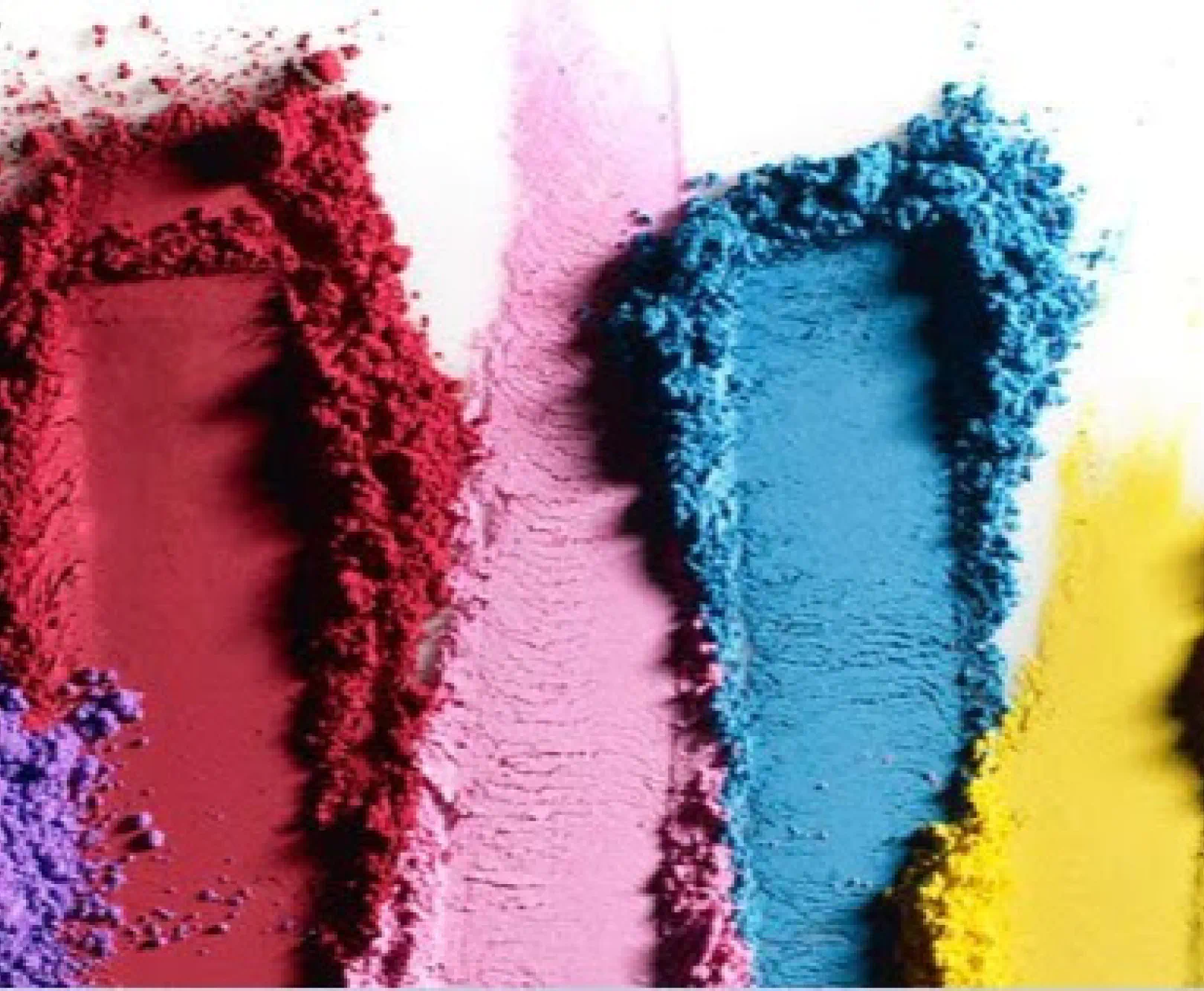 Colorful makeup powders are brushed across a white background. They include purple, red, pink, blue and yellow.